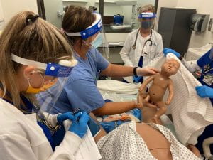 Students participating in birthing sim with manikin