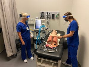 Two nursing students working with simulator